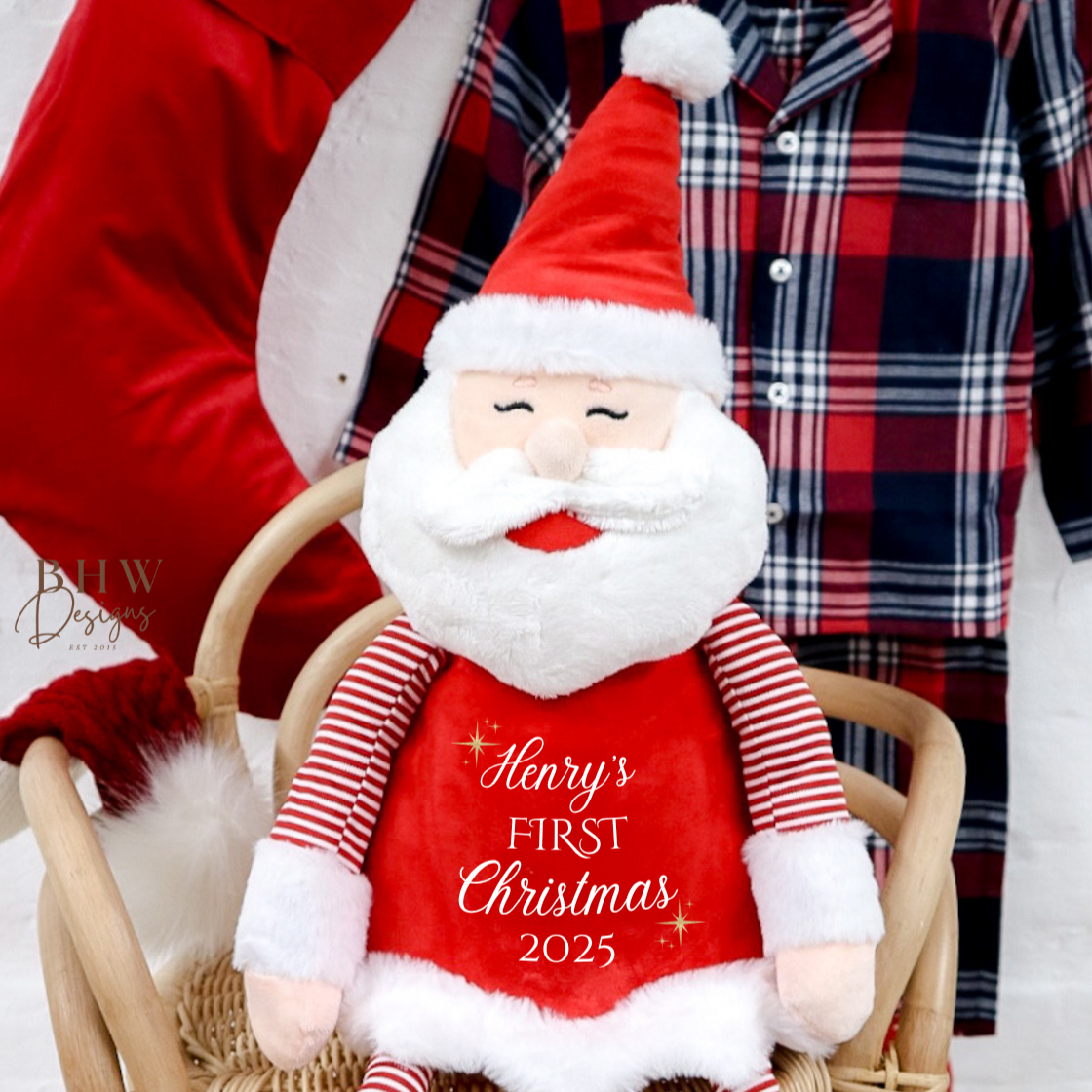 Plush Santa Claus toy with 'Harry's First Christmas 2023' text, sitting on a chair.