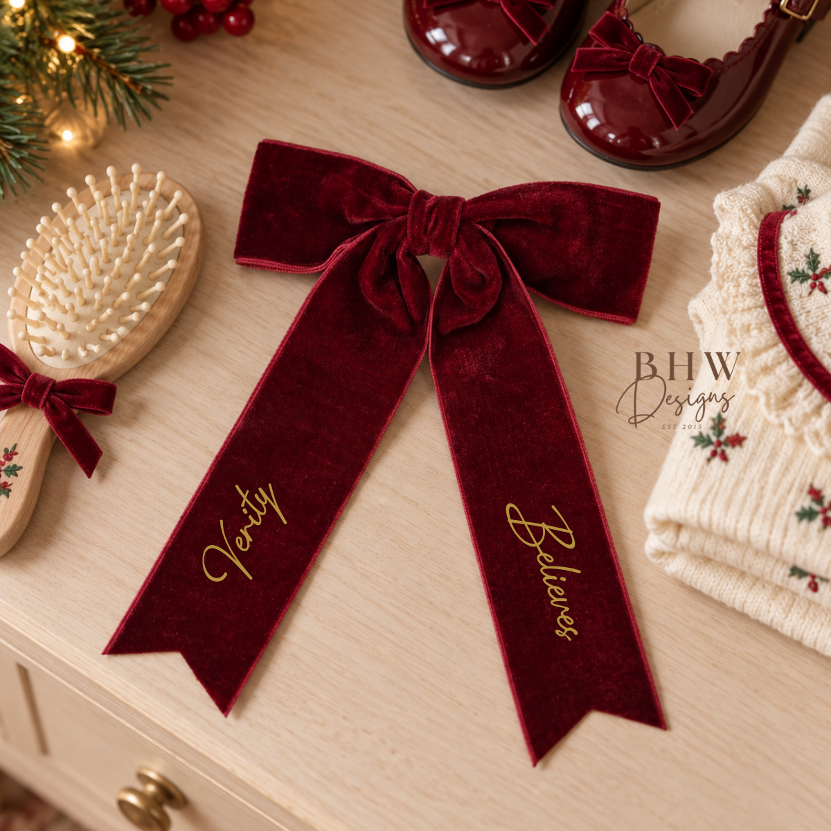 A deep burgundy velvet ribbon hair bow with gold script personalised with name a believes 