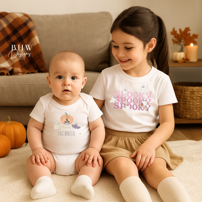 Two children wearing Halloween-themed shirts sitting on a blanket with pumpkins around.