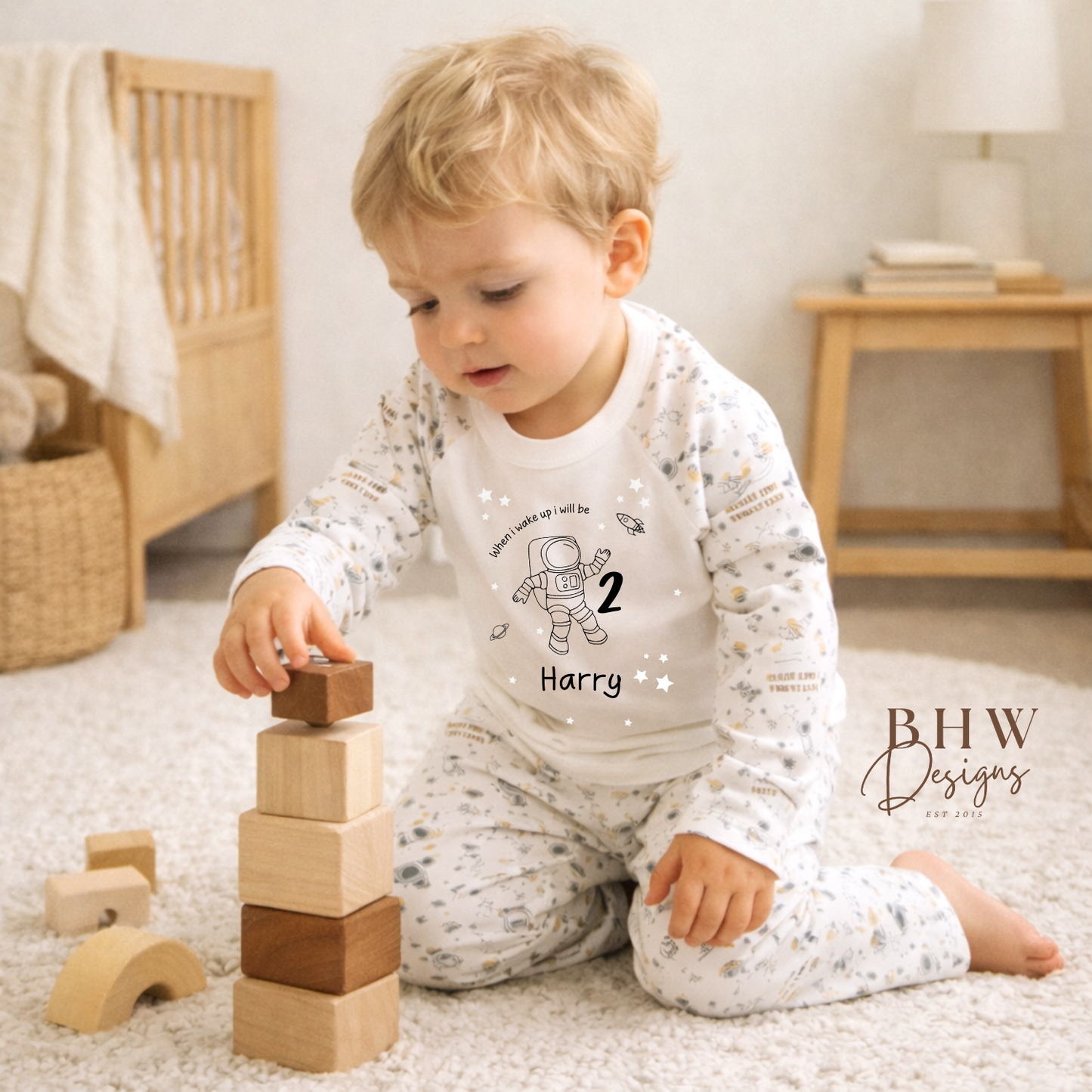 Child playing with wooden blocks in a home setting, wearing space theme pyjamas with when I wake up I will be age and name