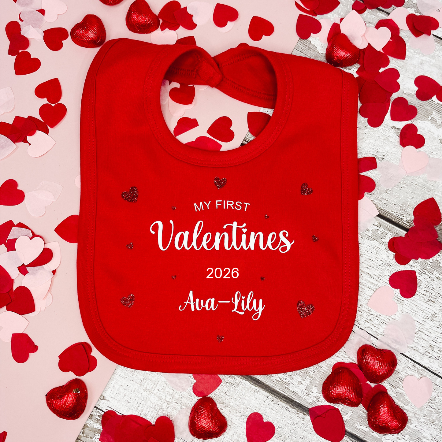 Red bib with 'My First Valentine's 2026 Ava-Lily' text on a heart-themed background