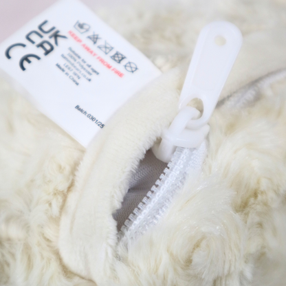 Close-up of a fluffy white garment with a zipper and a label on a light background