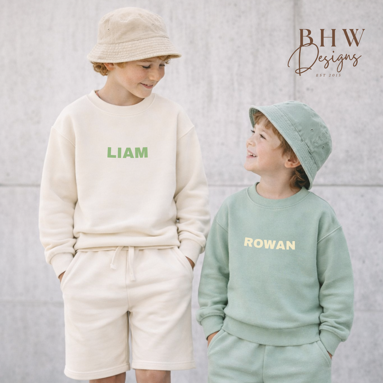 Two children wearing matching outfits with names printed on them, wearing matching bucket hats. 