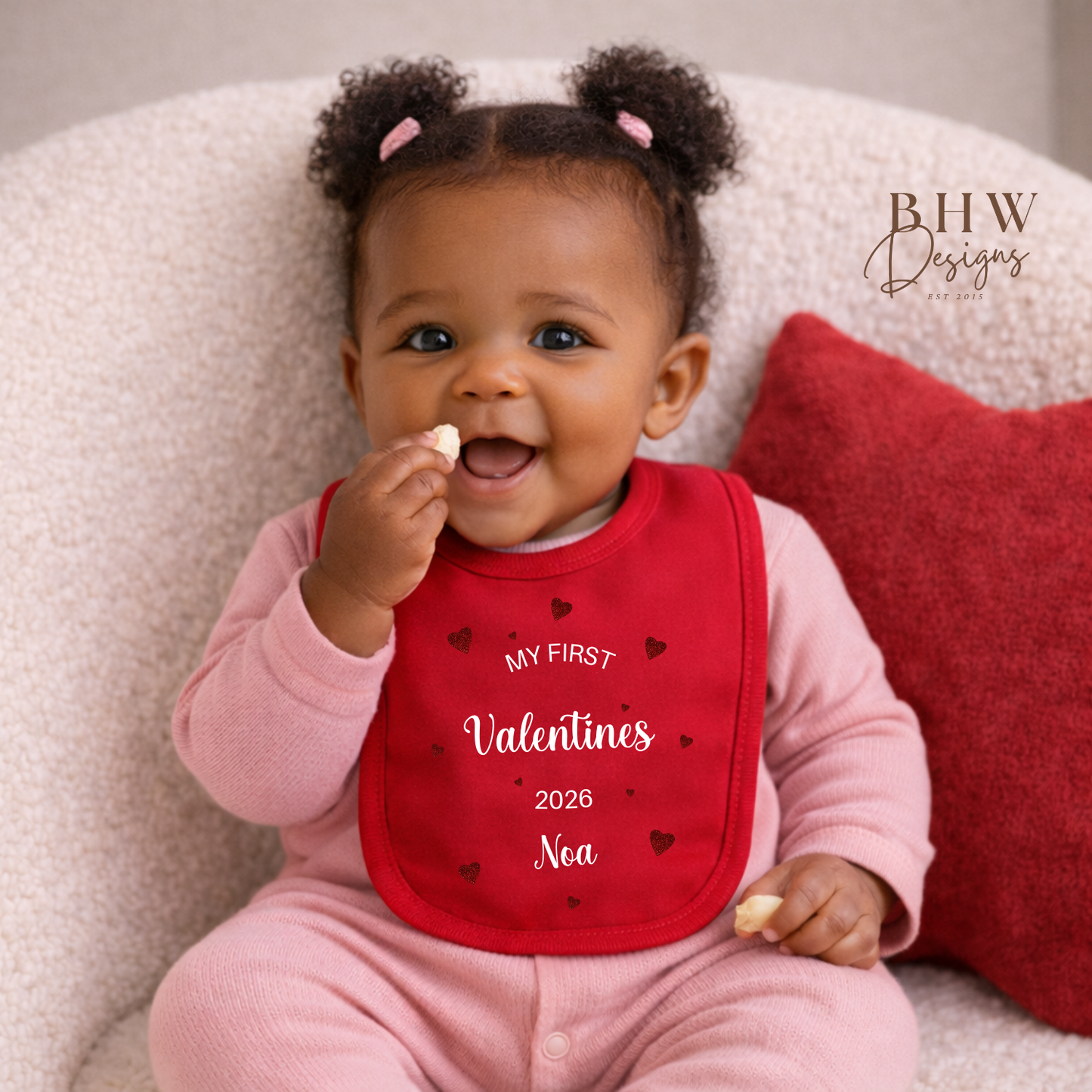 Baby wearing a red bib with 'My First Valentine's 2026' text, sitting on a soft surface.