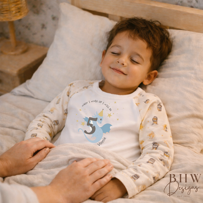 Child in pajamas with a birthday design lying on a bed, holding a hand.
