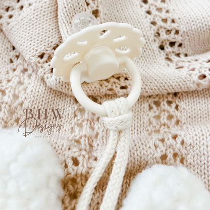 White baby teether on a textured beige fabric background