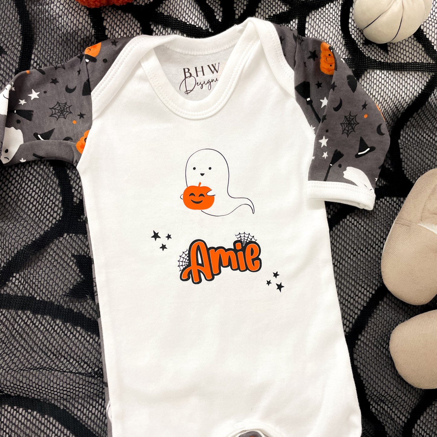 Halloween-themed baby onesie with ghost design and 'Amie' text on a decorative background.