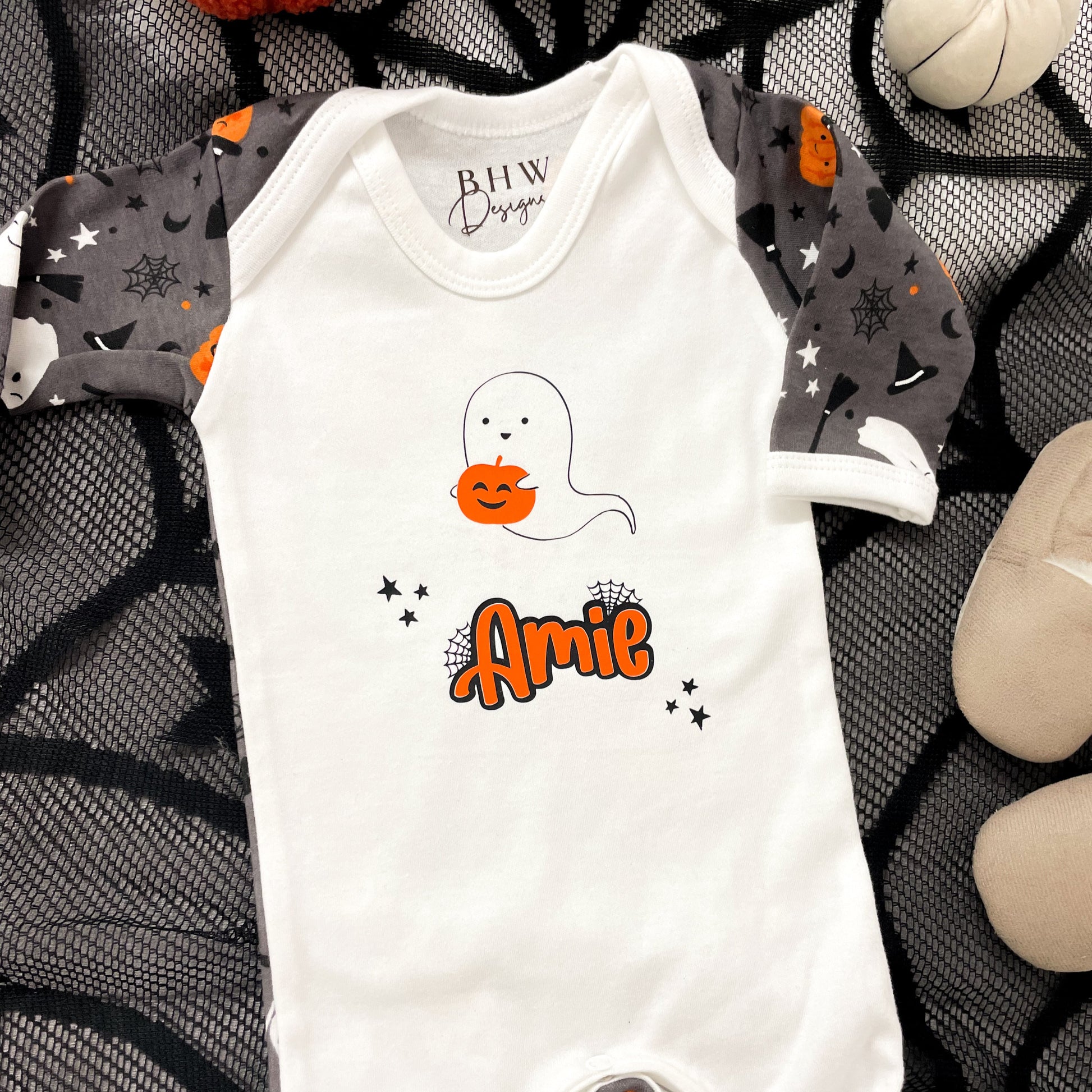 Halloween-themed baby onesie with ghost design and 'Amie' text on a decorative background.
