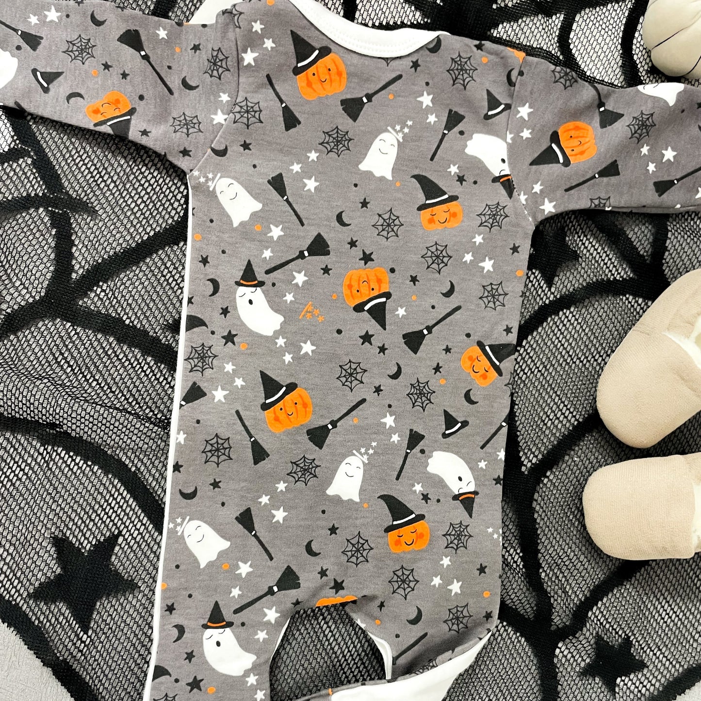 Grey baby onesie with Halloween pattern on a spider web background