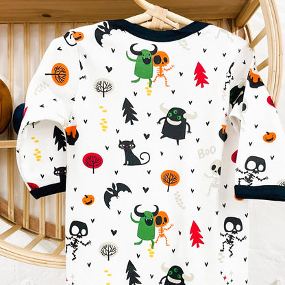 Long-sleeve bodysuit with Halloween-themed pattern on a hanger against a wooden shelf background.