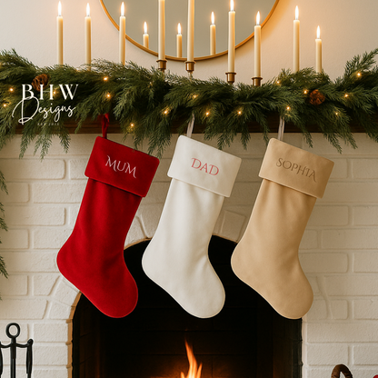 Three Christmas stockings labeled 'MUM', 'DAD', and 'SOPHIA' hanging above a fireplace with candles and greenery.
