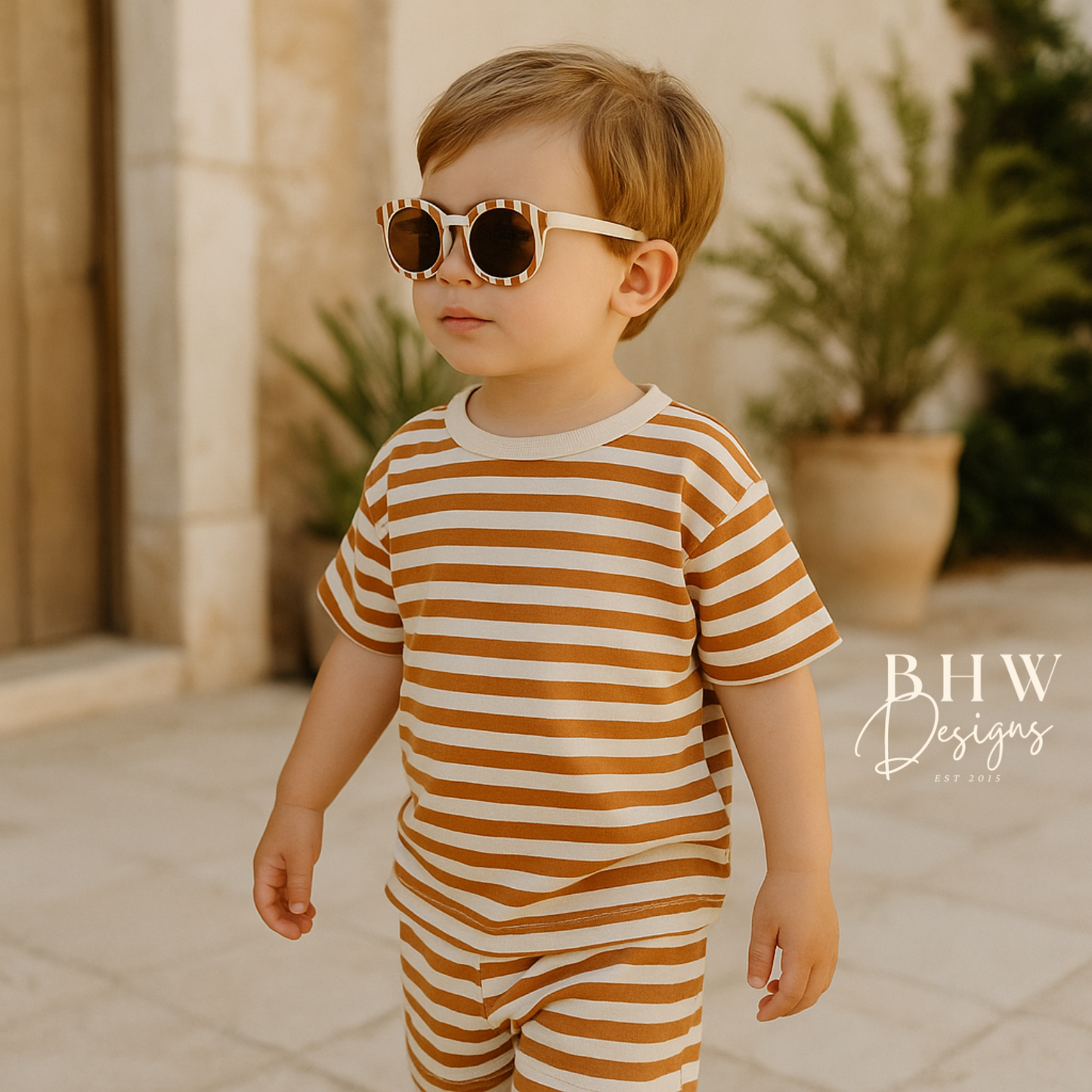 Child wearing a striped outfit and sunglasses outdoors